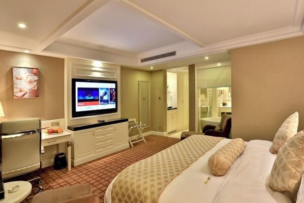 Een hotelkamer met een bed, een bureau, een televisie en een badkamer die door een geopende deur zichtbaar is.