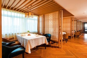 Uma sala de jantar tradicional japonesa, com piso de madeira, uma mesa posta para dois e uma porta de correr.