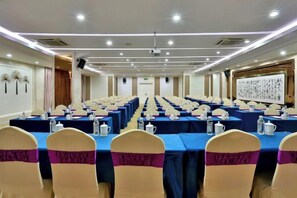 A conference room with multiple tables, chairs, and a projector screen. - Zhong'an Huana Holiday Hotel (Hangzhou)