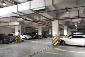 Garagem de estacionamento com vários níveis, carros estacionados em vagas demarcadas, sinalização clara e barreiras de segurança.