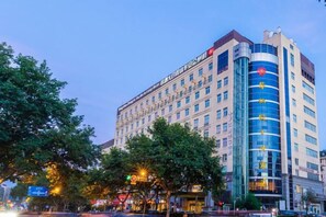 Un hôtel à plusieurs étages, avec un bâtiment d’angle imposant, de grandes fenêtres et une entrée bien visible.