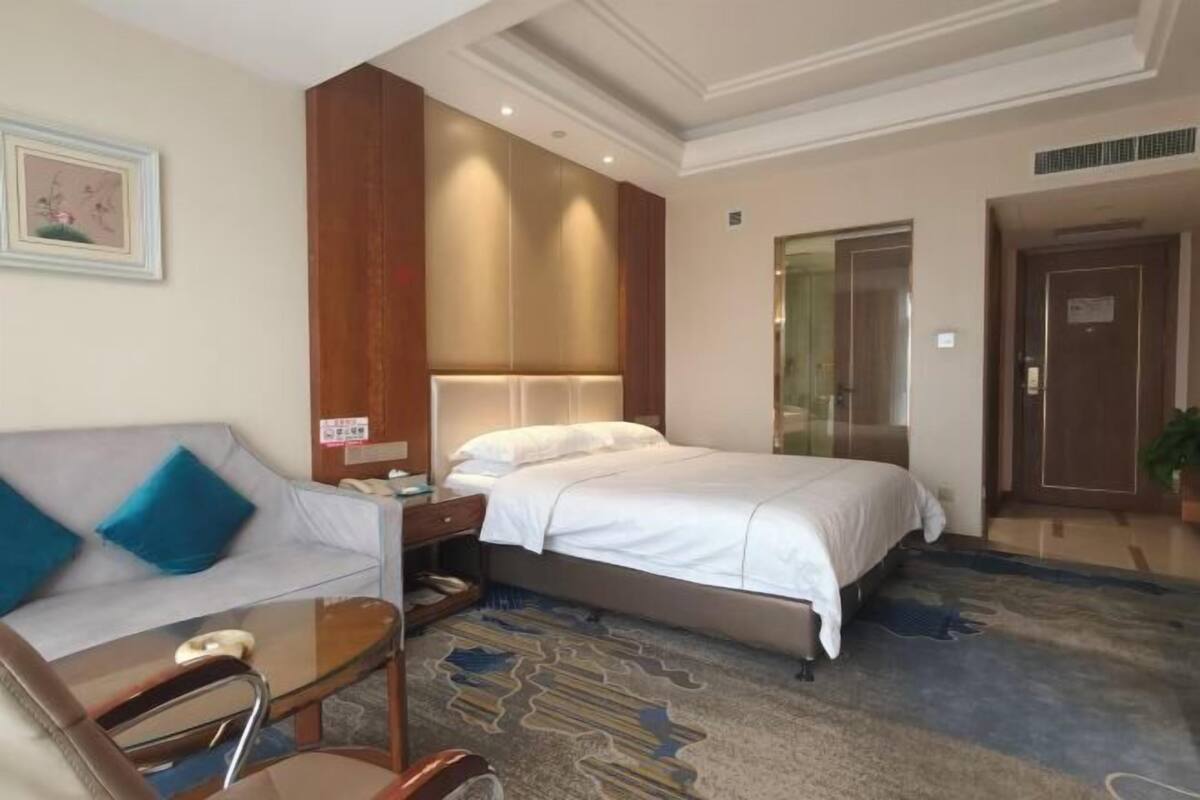 Una habitación de hotel con cama, sofá, escritorio y puerta.