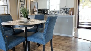 Una cucina moderna con isola centrale, illuminazione a sospensione e zona pranzo con sedie imbottite blu.