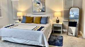 A bedroom with a bed, two bedside tables, a mirror, and a ceiling fan. - Coastal Home w/ Outdoor Living, 10 min to Beach (Vero Beach)