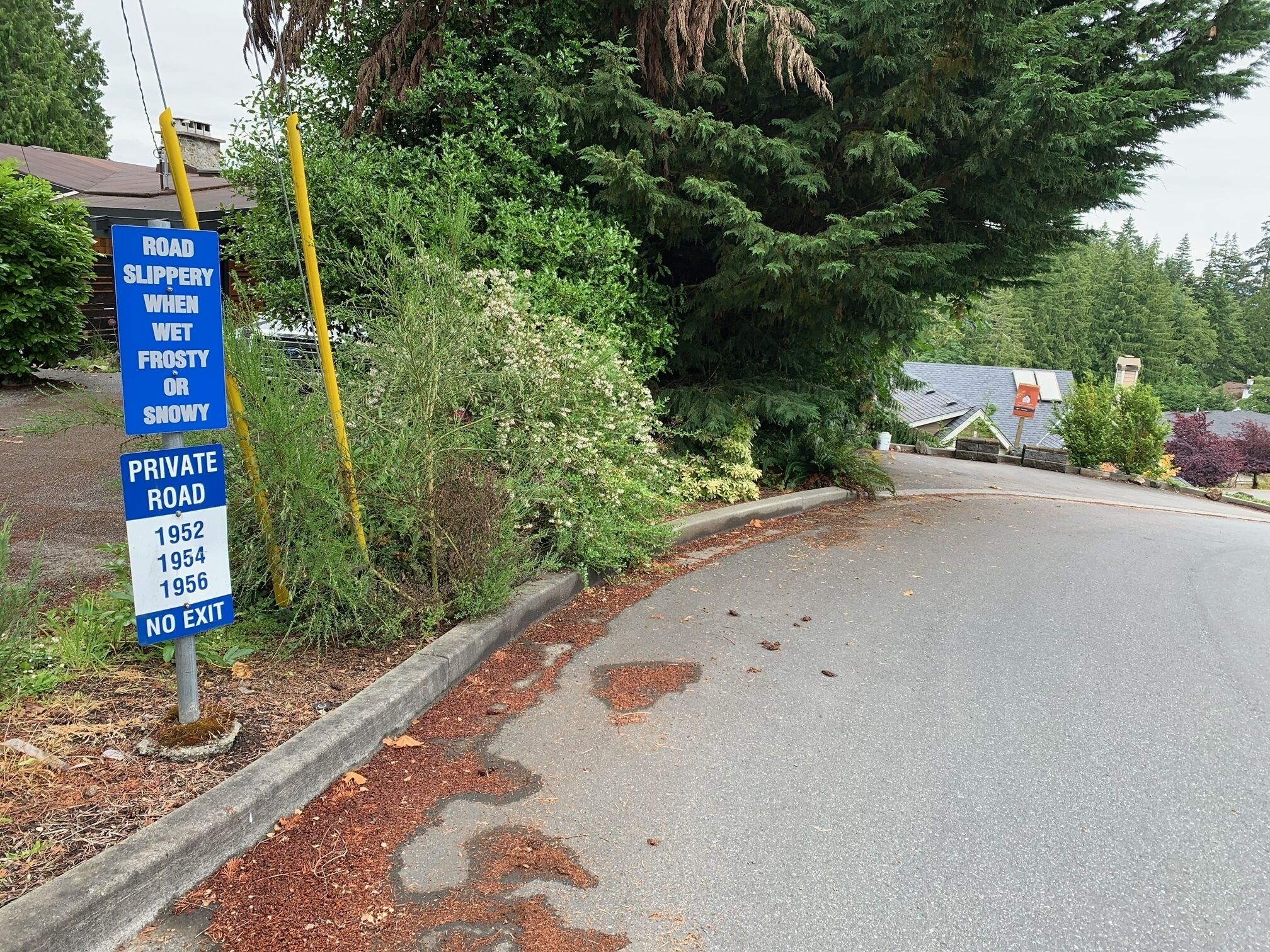 A private road sign warning of slippery conditions when wet, frosty, or snowy.