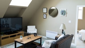 A living room with a TV, sofa, coffee table, and a skylight. - Quiet, cozy 1 bedroom suite, w/ separate entrance. Now with A/C! (North Saanich)