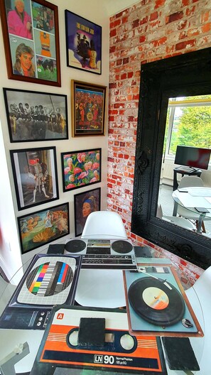 A room with a brick wall, a window with a view, and a desk with a turntable and audio equipment.