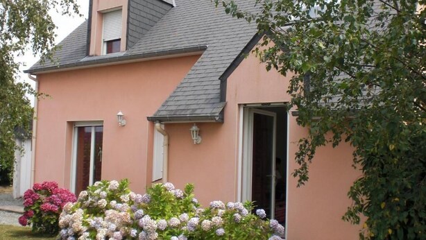 A two-story house with a peach exterior, a gray roof, and a front door. There are two windows on the first floor and a small balcony on the second floor. - DINARD - LA RICHARDAIS T2- NEAR SEA AND RANCE (La Richardais)