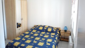 A bedroom with a bed, a wardrobe, a nightstand, and a radiator. - DINARD - LA RICHARDAIS T2- NEAR SEA AND RANCE (La Richardais)