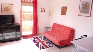 A living room with a sofa, a TV, a dining table, and a Union Jack rug. - DINARD - LA RICHARDAIS T2- NEAR SEA AND RANCE (La Richardais)