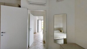 A hotel room with a bed, a mirror, and a door leading to another room. - Blu House a Castelsardo (Castelsardo)