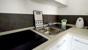A modern kitchen with a black sink, stainless steel faucet, and a white kettle. - Blu House a Castelsardo (Castelsardo)