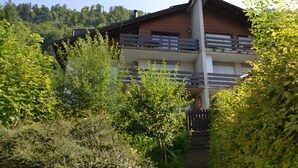 A two-story building with a wooden facade, a balcony on the upper floor, and a staircase leading to the entrance. - Two-bedroom Apartment for 4-5 Guests With Lake and Mountain Views (Emmetten)