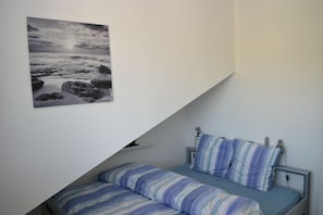 A bedroom with a bed, pillows, a bedside table, and a wall-mounted picture.