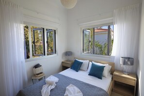 A hotel room with a bed, two bedside tables, a lamp, and a window with curtains.