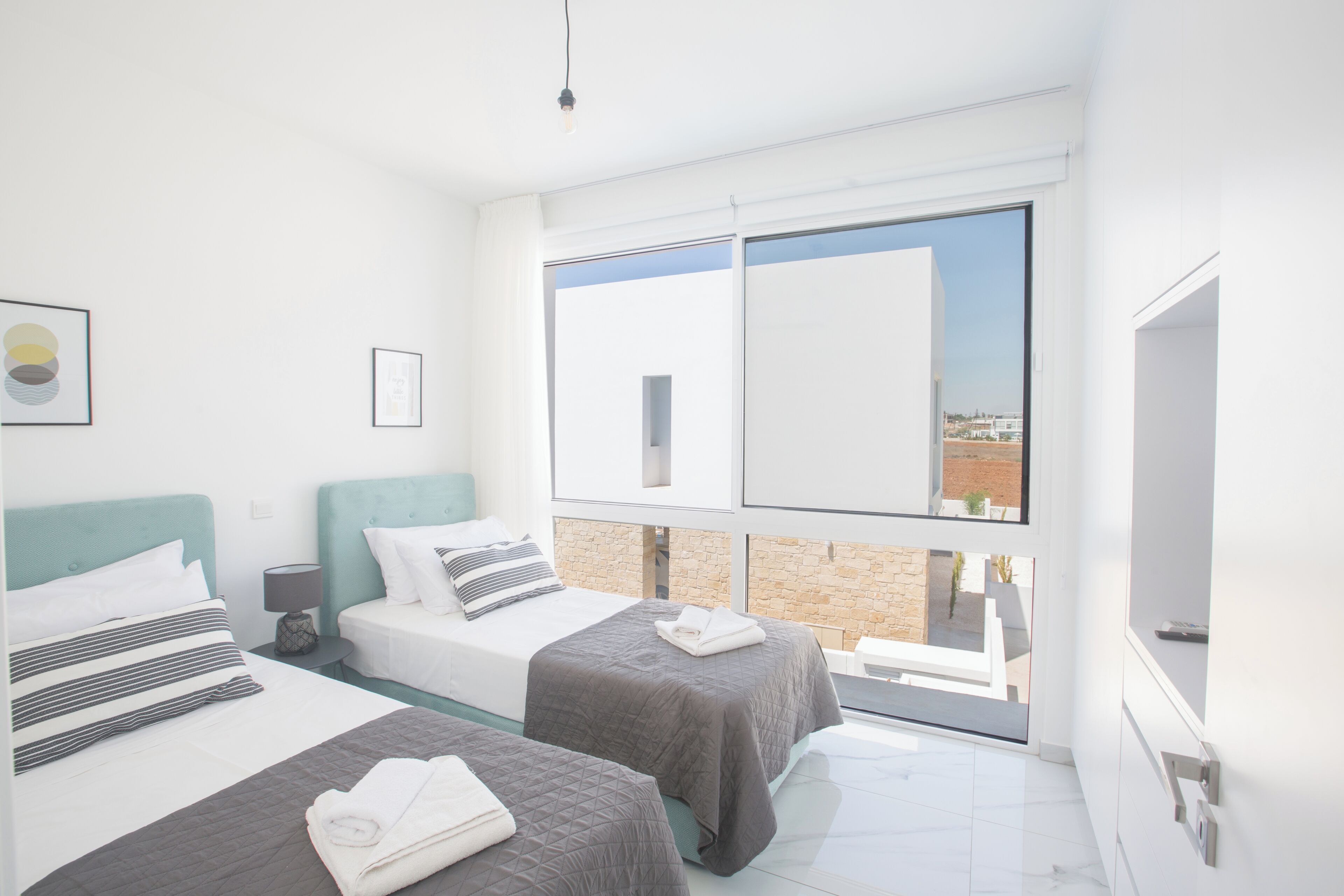 Une chambre d’hôtel moderne avec deux lits, une grande fenêtre et une vue sur la ville.