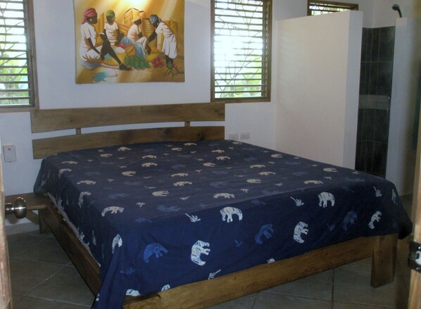 A bedroom with a bed, a wooden headboard, a painting on the wall, and a window with blinds. - Pretty Caribbean Style Villa (Las Terrenas)