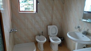 Une salle de bain avec une baignoire, deux toilettes, un bidet et un lavabo.