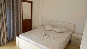 Une chambre à coucher comprenant un lit, une table de chevet, une commode et une porte avec des rideaux.