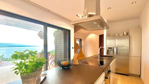 Una cocina moderna con una isla grande, electrodomésticos de acero inoxidable y vista al mar.