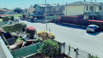 Uma rua residencial com casas, um carro estacionado e céu limpo.