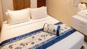 A bedroom with a bed, a wooden wardrobe, a wall-mounted fan, and a bedside table. - Modern Chalet With Garden Views and Shared Pool in Port Said (Al-Manasrah)
