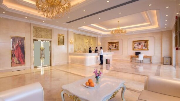 A spacious lobby with a reception desk, a chandelier, and a marble floor.