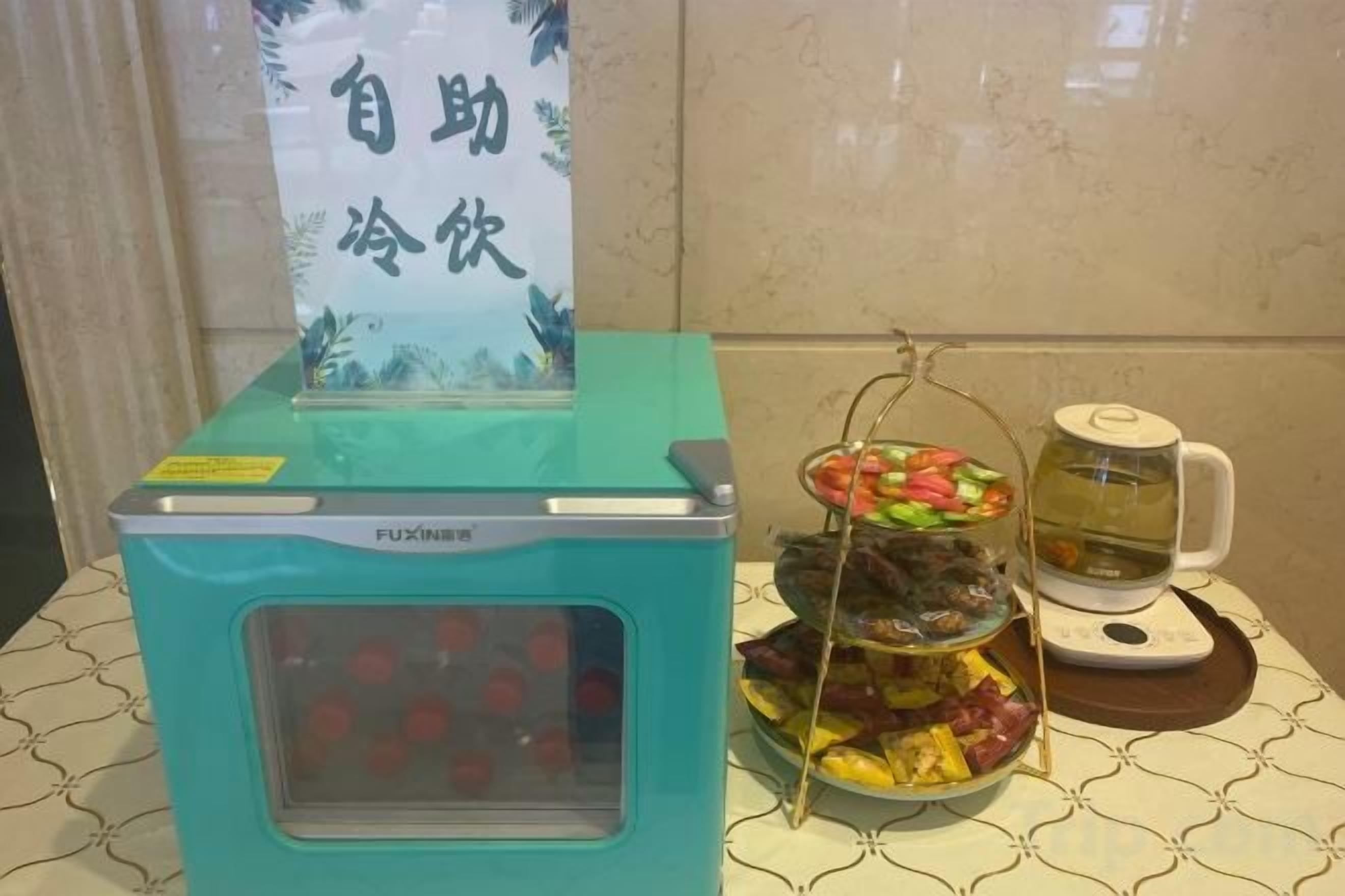 A self-service beverage machine with a selection of drinks, a tray of assorted fruits, and a teapot.