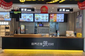 A restaurant counter with digital menu displays, a cash register, and a beverage dispenser. - Vienna 3 Best Hotel (Shenzhen Longhua Dalang Commercial Center) (Shenzhen)