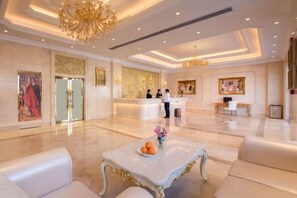 A hotel lobby with a reception desk, seating area, and artwork.