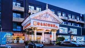 A hotel with a classical facade, a prominent entrance, and a parking area in front.