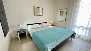 A neatly arranged bedroom with a bed, bedside tables, and framed pictures on the walls. - Holiday Home With Garden and Shared Pool (Caorle)