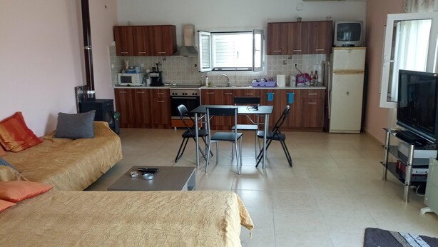 Un ambiente compatto con angolo cottura, divano, tavolo da pranzo e televisione.