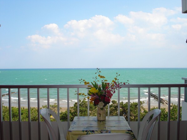 A balcony with a table and chairs, overlooking a beach and the ocean. - Seaview Flat Just 70mt From the sea (Caorle)
