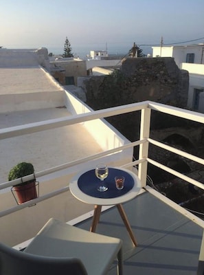 A balcony with a table, a potted plant, and a glass of water.