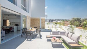 A modern outdoor living area with a dining table, chairs, a sofa, and a coffee table. - 4 Bedroom Villa in Protaras Center - Protaras Vie Bleu Villa Vb3 (Paralimni)