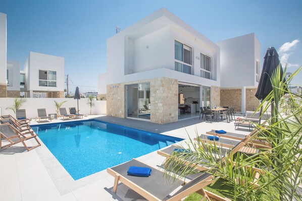 A modern two-story building with a swimming pool, outdoor seating, and a patio area. - 4 Bedroom Villa in Protaras Center - Protaras Vie Bleu Villa Vb3 (Paralimni)