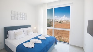 A bedroom with a large window, a bed with white linens, and a view of a landscape. - 4 Bedroom Villa in Protaras Center - Protaras Vie Bleu Villa Vb3 (Paralimni)