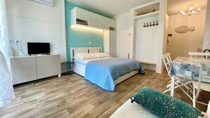 Un dormitorio con cama, mesita de noche, televisión y una pequeña mesa con sillas.