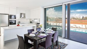 A modern kitchen with white cabinets and a dining area with a table set for six. - Protaras Holiday Villa Bp3 (Paralimni)