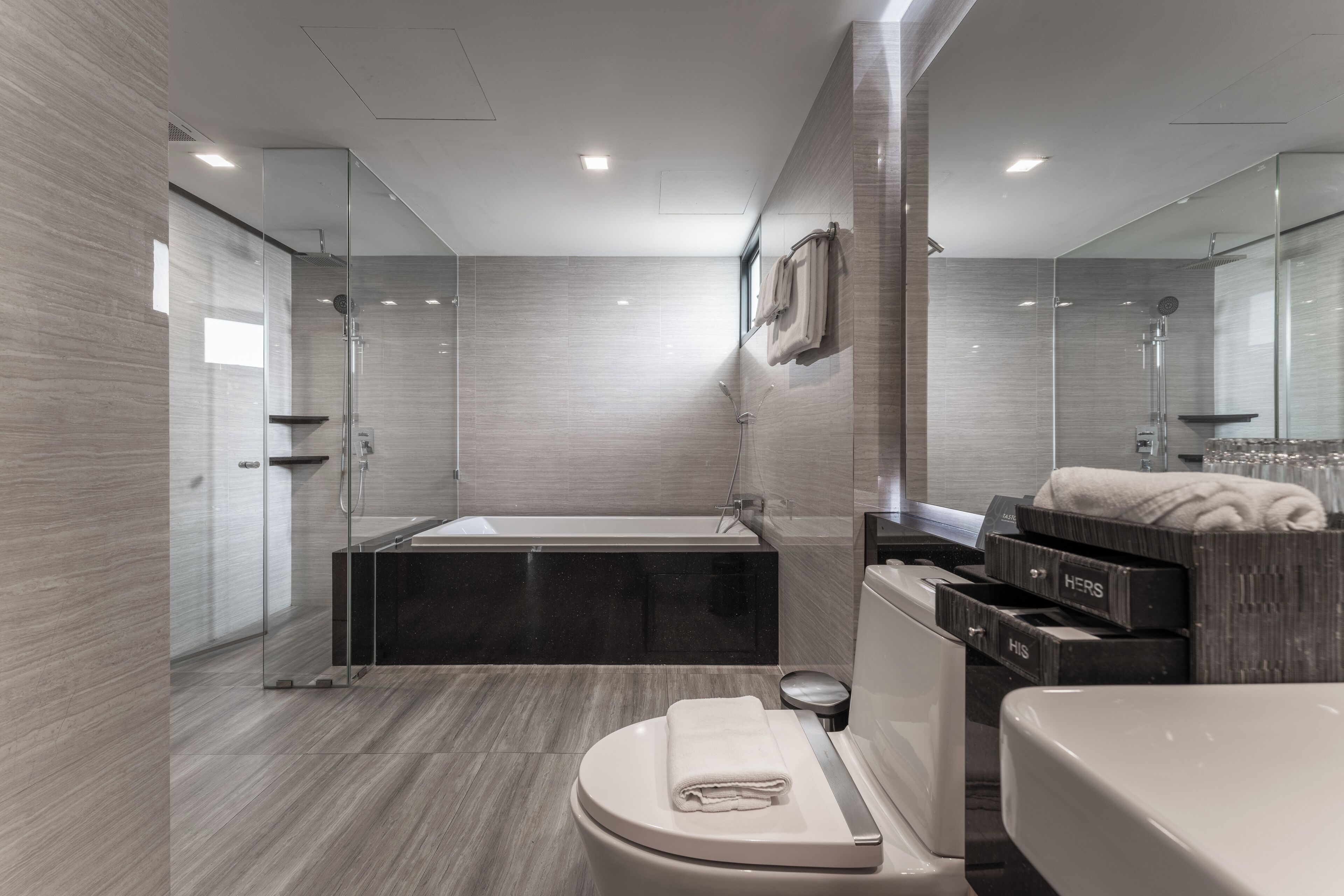 A modern bathroom with a glass-enclosed shower, a freestanding bathtub, a toilet, and a vanity with a mirror.