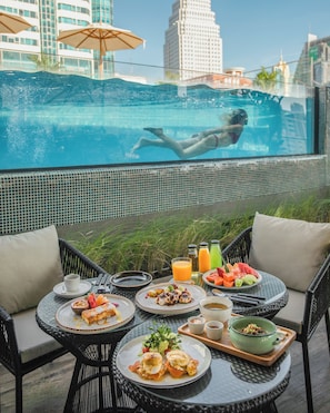 A dining area with outdoor seating overlooking a swimming pool, featuring a cityscape view. - Tastoria Collection Hotel Sukhumvit (Bangkok)
