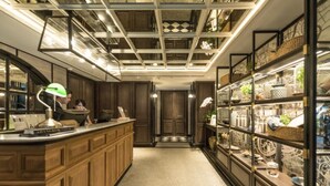 A modern kitchen with wooden cabinets, a central island, and a glass display case on the right. - Tastoria Collection Hotel Sukhumvit (Bangkok)