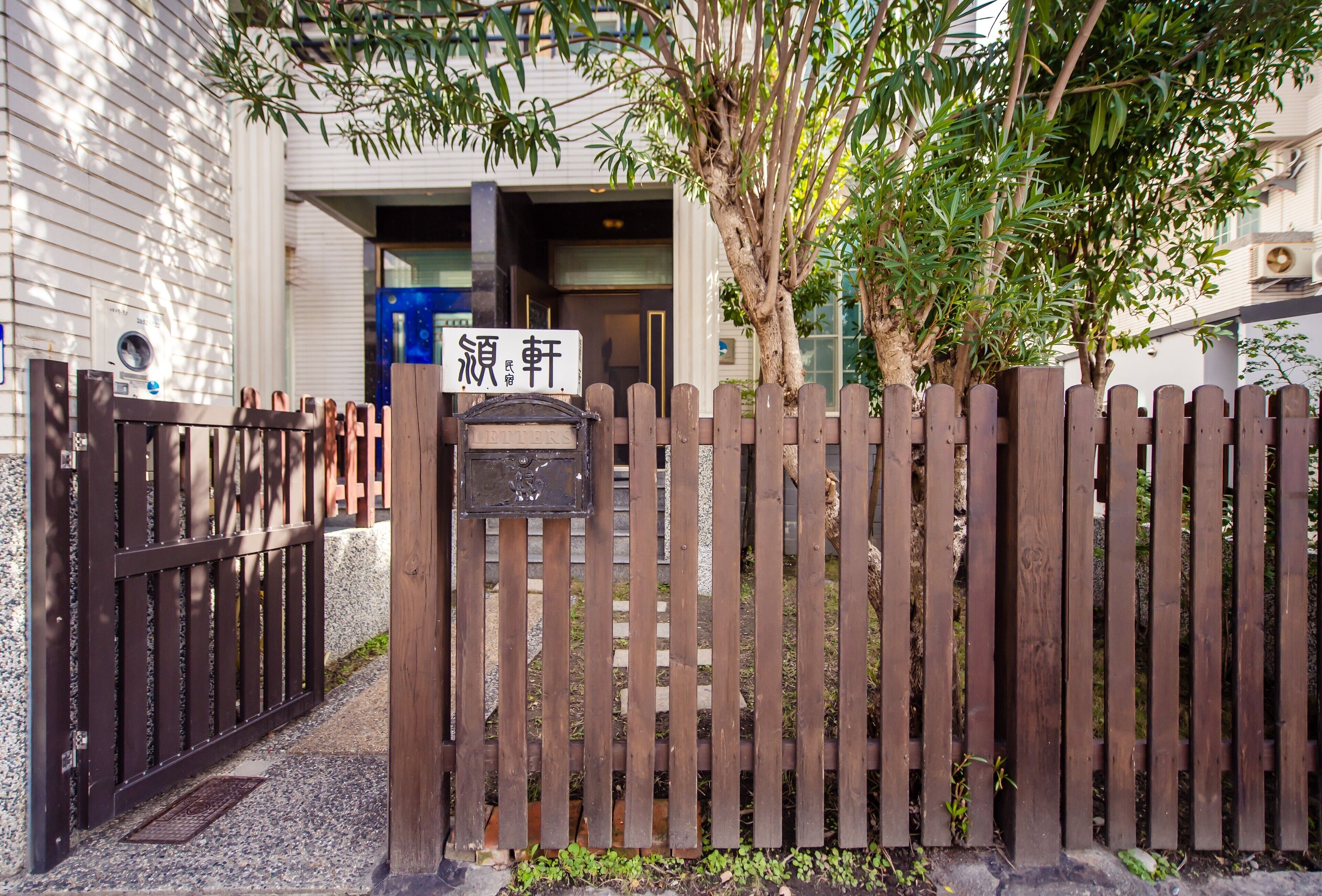 A wooden gate with a mailbox and a sign in front of a building.