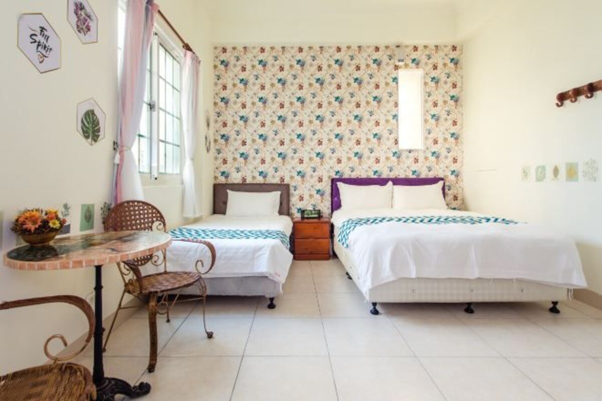 A room with two beds, a small table, and a chair.