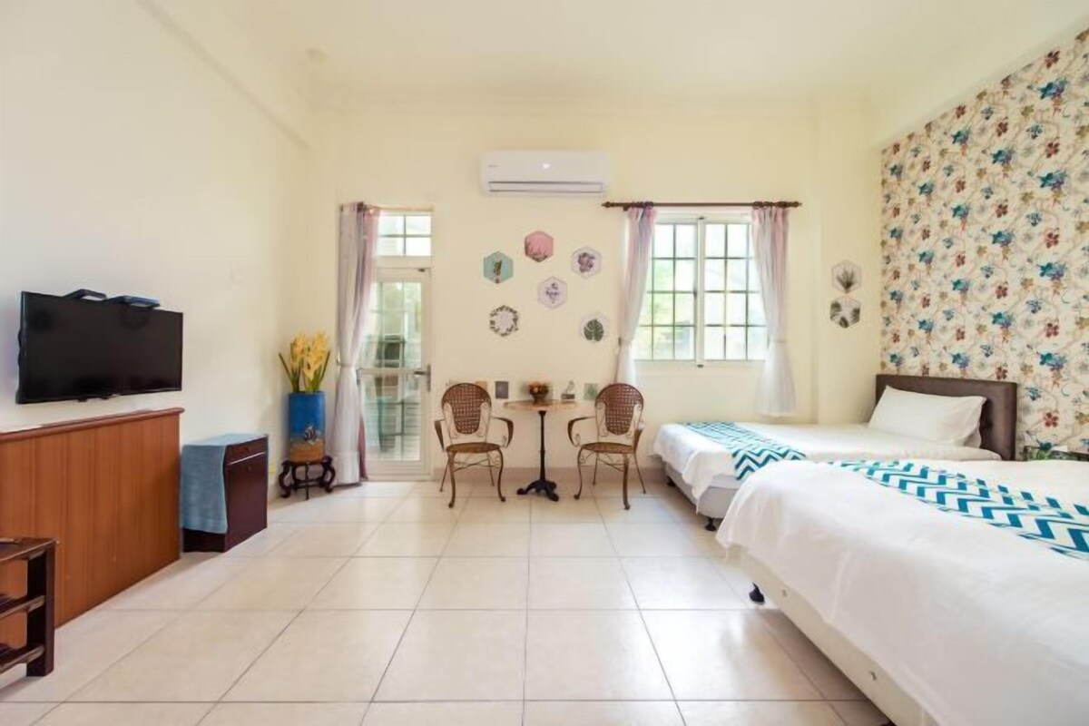 Habitación de hotel con cama, televisión, escritorio y sillas, y ventana con cortinas.