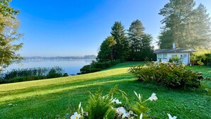 A serene lakeside property with a well-maintained lawn, a small white house, and dense trees. - Haus Se[e]renity - Cozy house by the lake (Hungen)