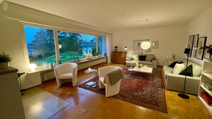 A spacious living room with a large window, a sofa, a coffee table, and a rug. - Haus Se[e]renity - Cozy house by the lake (Hungen)