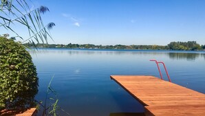 A wooden dock extending into calm water with a clear sky. - Haus Se[e]renity - Cozy house by the lake (Hungen)