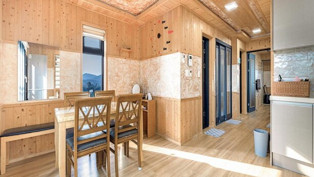 Un intérieur en bois comprenant un coin repas, une cuisine et une salle de bain.